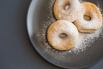 Sugary donuts on a black plate on a dark table background. in a windows light. Breakfast concept