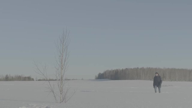 Man goes through the snowy field. A person on a snowy field. Man walking on deep snowy field