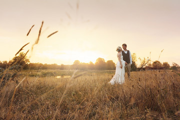 Newlyweds standing in the field with ears