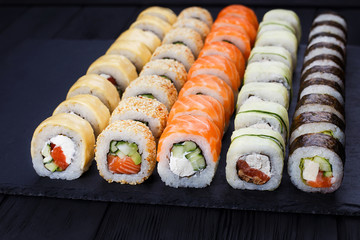 Colorful delicious set of sushi served on  black slate, close up. Japanese cuisine, restaurant menu photo.