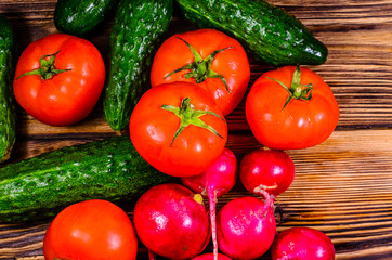 Ripe tomatoes, radish and cucumbers on wooden table. Top view