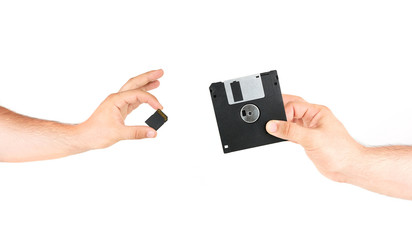 Hands Holding Small Memory Card Versus Old Floppy Disk Concept Technology Isolated On White Background