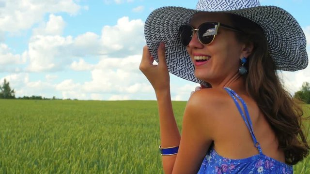 Close up shot of smiling caucasian woman in white hat in the green field