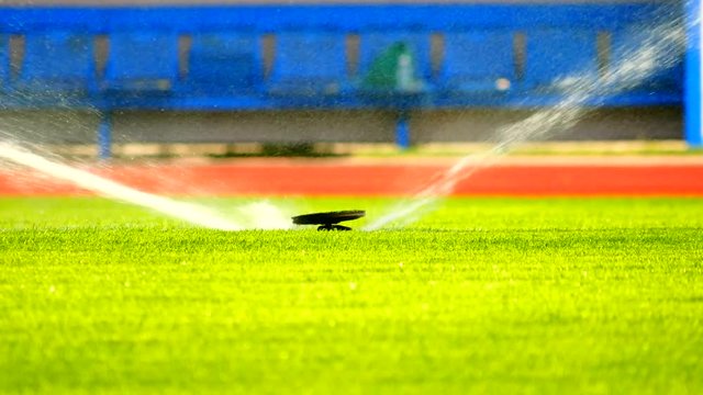 Sprinkler Watering a Sports Field. Working sprinklers with strong water spray