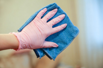A woman is cleaning in a room with gloves