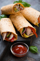 Close-up of tortilla wraps filled with roast chicken and fresh vegetables, selective focus, vertical shot