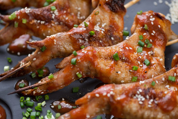 Close-up of grilled chicken wings with sauce, sesame and green onion, selective focus