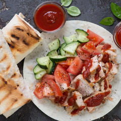 Close-up of shaurma or shawarma with grilled chicken meat, fresh vegetables and lavash, top view