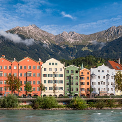 Colorful buildings in Innsbruck surrounded by mountains the river in front of the buildings