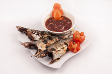 Delicious grilled mackerel fish served with taramind sauce and tomato, famous in malaysian food.