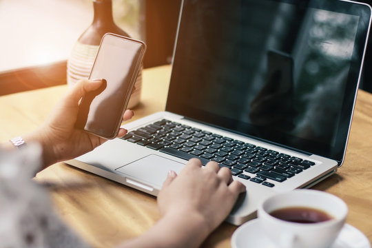 Close Up of woman hands using mobile phone and laptop computer with blank copy space screen for your advertising text message or content business in the Vintage effect.