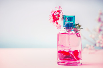 Pink Bottle of perfume with flowers, natural cosmetic product or beauty concept on pastel blue...