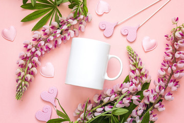 White coffee mug with lupine flowers and hearts on pink background.