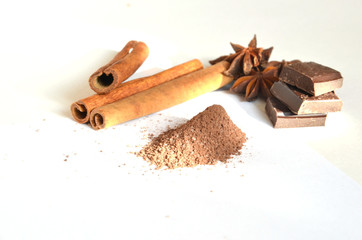 Three cinnamon sticks anise in the form of a flower cocoa powder, cube of chocolate