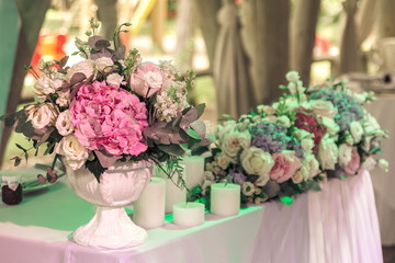 Bouquets of roses and candles on decorated wedding table in rastuurant.