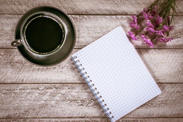 flowers on wooden table. copy space. workspace with notebook and coffee cup. celebration template concept.