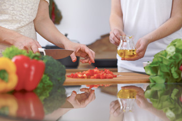 Obraz na płótnie Canvas Close-up of four human hands are cooking in a kitchen. Friends having fun while preparing fresh salad. Vegetarian, healthy meal and friendship concept