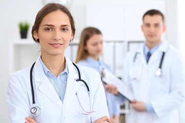 Fototapeta premium Young beautiful female doctor smiling on the background with patient in hospital