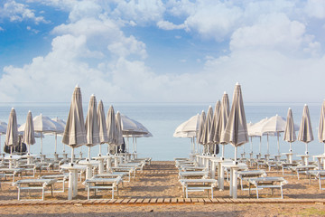 Umbrellas and a lounger on the beach near the water. Preparation for the tourist sison. The tourist season is buried. Beach without people