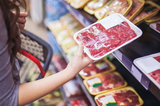 Close up of woman holding wrapped meat in grocery store