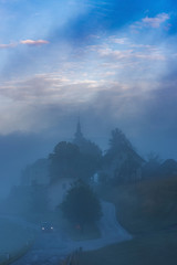 Car driving road leading to Church of saint Nikolaja in Sorica, Slovenia at dense fog