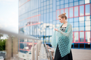 A beautiful girl in a black top and a long skirt on a walk against a blue mirror building. A girl...