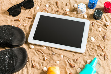 Fototapeta na wymiar Online poker game on the beach with digital tablet and stacks of chips. Top view
