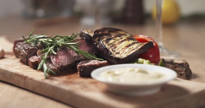Slide slow motion shot of rib eye steak with grilled vegetables