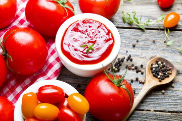 Ketchup with tomatoes on wooden background