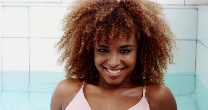 black mixed race woman in swimming pool lifted up head and watching at camera