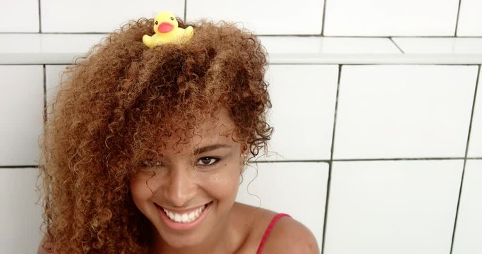black woman's portrait sitting in bath with a duck on her head