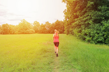 Young woman running from back with strong light.