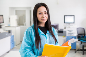 Attractive female lab worker making medical research in modern laboratory. Scientist holding...