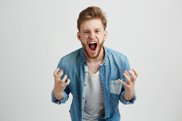 Angry rage young man with beard shouting screaming gesturing over white background.