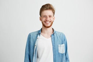 Portrait of young handsome hipster man with beard smiling laughing looking at camera over white...
