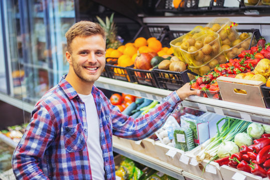 Young man buying fruit in grocery store.