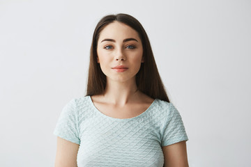 Portrait of young beautiful brunette girl looking at camera smiling over white background.