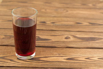 Cherries juice in glass on old wooden background