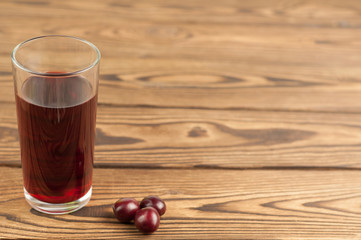 Cherries juice in glass on old wooden background