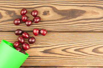 Red fresh cherries and plastic glass on old wooden background