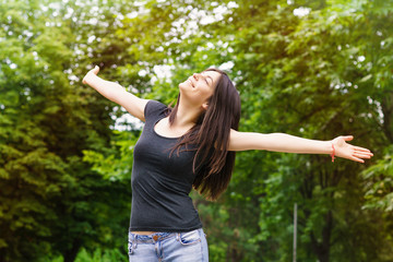Young Woman in sunny park with outstretched arms