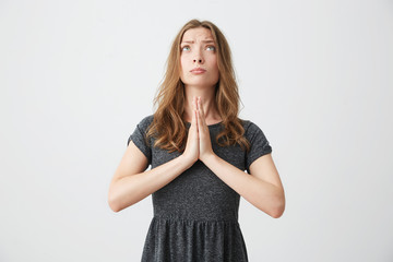 Portrait of young beautiful girl looking up praying over white background.