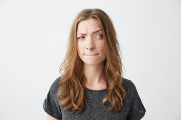 Young beautiful girl suspiciously looking in side thinking over white background.