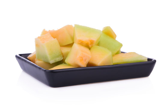 Melon slices on a black plate Isolated on White Background.