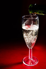 Champagne pouring in a glass from a bottle on red background - 163645277