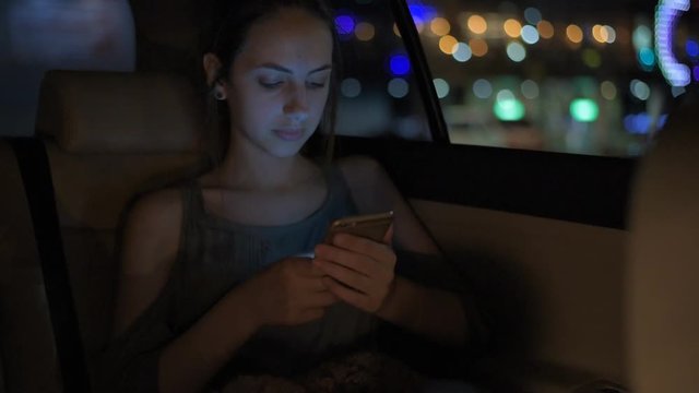 Young adult female in taxi using smart phone.