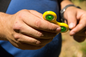 Man playing with fidget spinner stress relieving toy outdoor