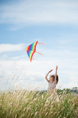Cute little girl with long hair holding kite in the field on summer sunny day