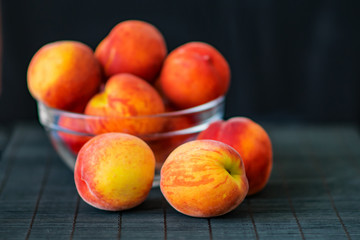 Ripe peaches in a transparent glass bowl on a black background. Summer fruits. Health Care Concept