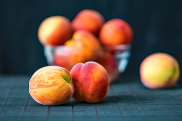 Ripe peaches in a transparent glass bowl on a black background. Summer fruits. Health Care Concept
